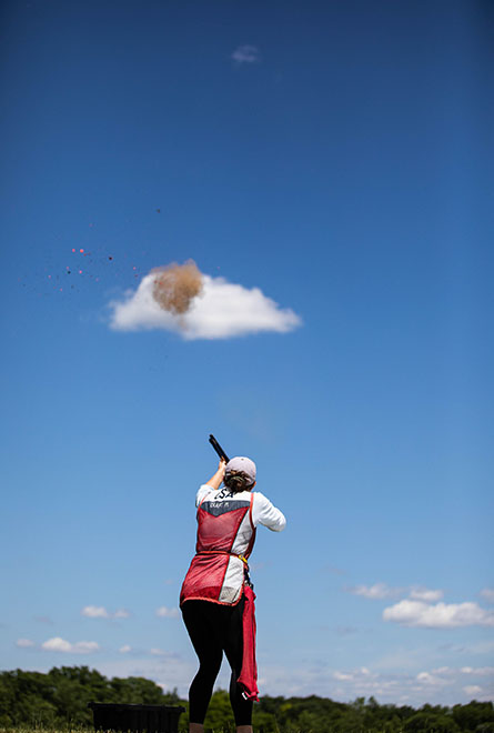 Athlete wearing USA Shooting vest shooting at a clay target.