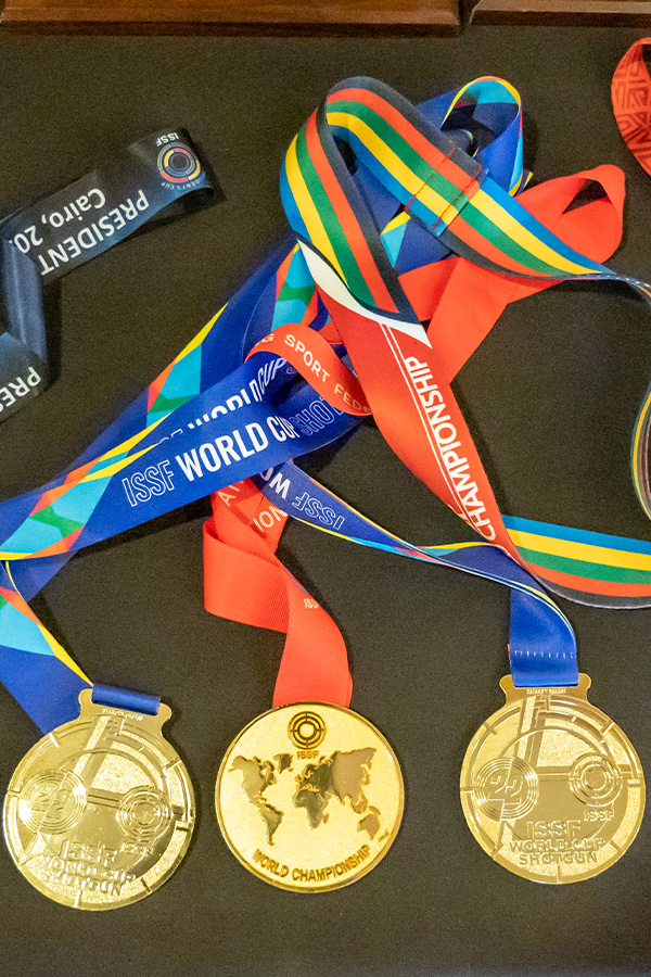 Various shooting medals with colorful ribbons are displayed on a table.