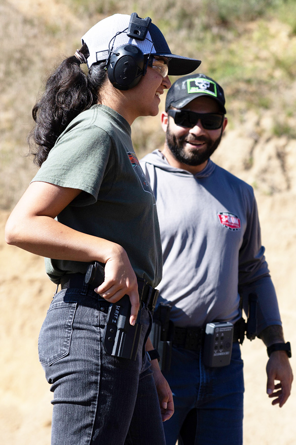 An image of a woman holstering her pistol at the range.